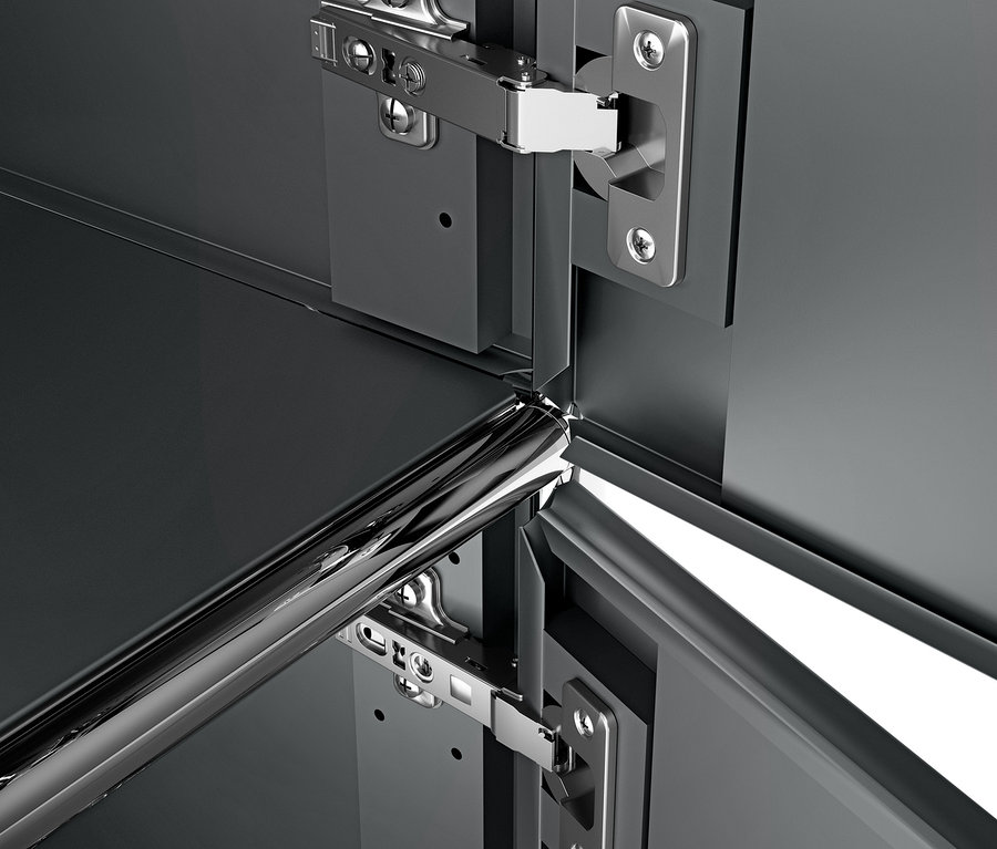 Detail šedého kovového kontejneru na kolečkách CN3 se 3 dvířky a chromovanými panty.