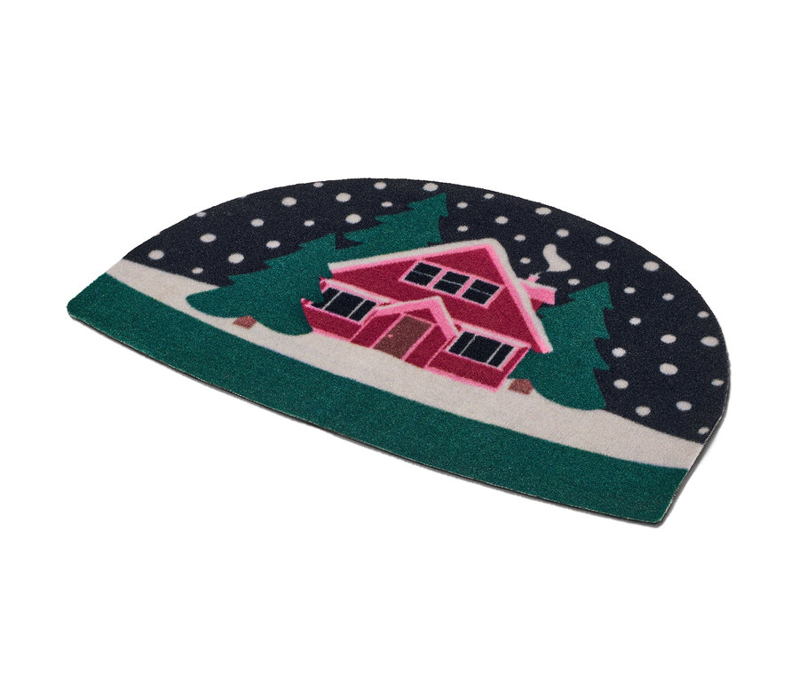 Rohožka s motivem zasněženého domu mezi stromy.