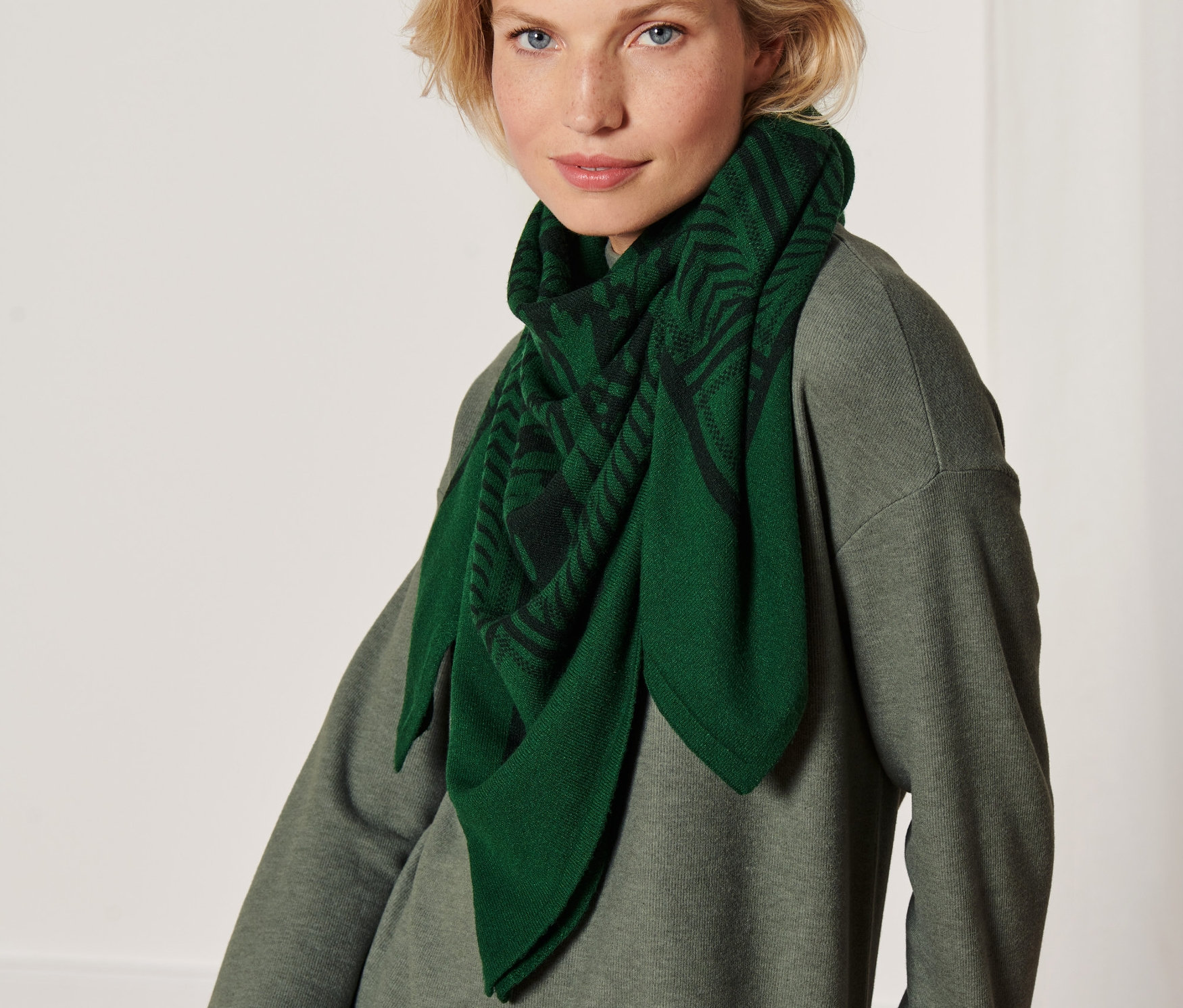 Blonďatá žena má na sobě pletenou šálu.