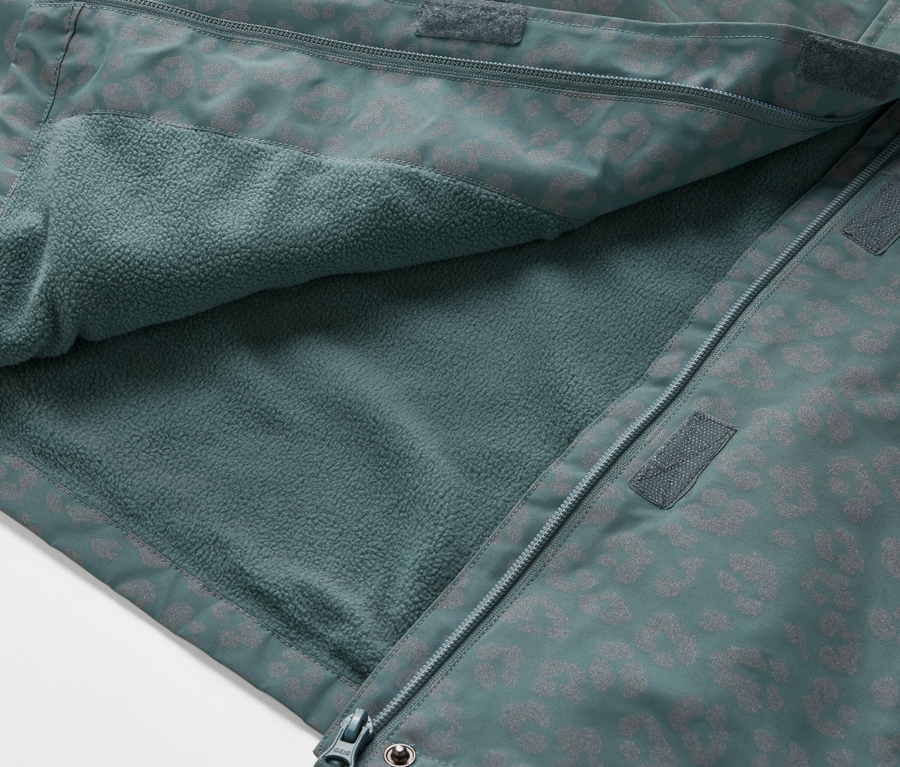 Detail dětské termo bundy do deště s reflexními prvky, rozepnuté a ukazující vnitřní fleecovou vrstvu.