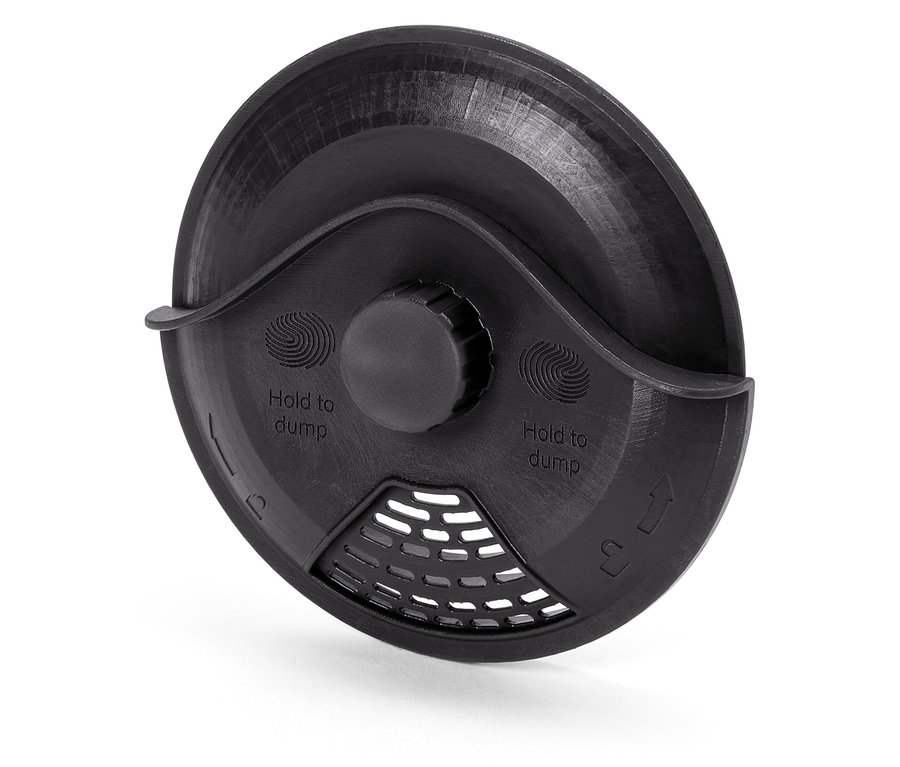 Detailní pohled na černý plastový kryt s nápisem "Hold to dump" a mřížkou.