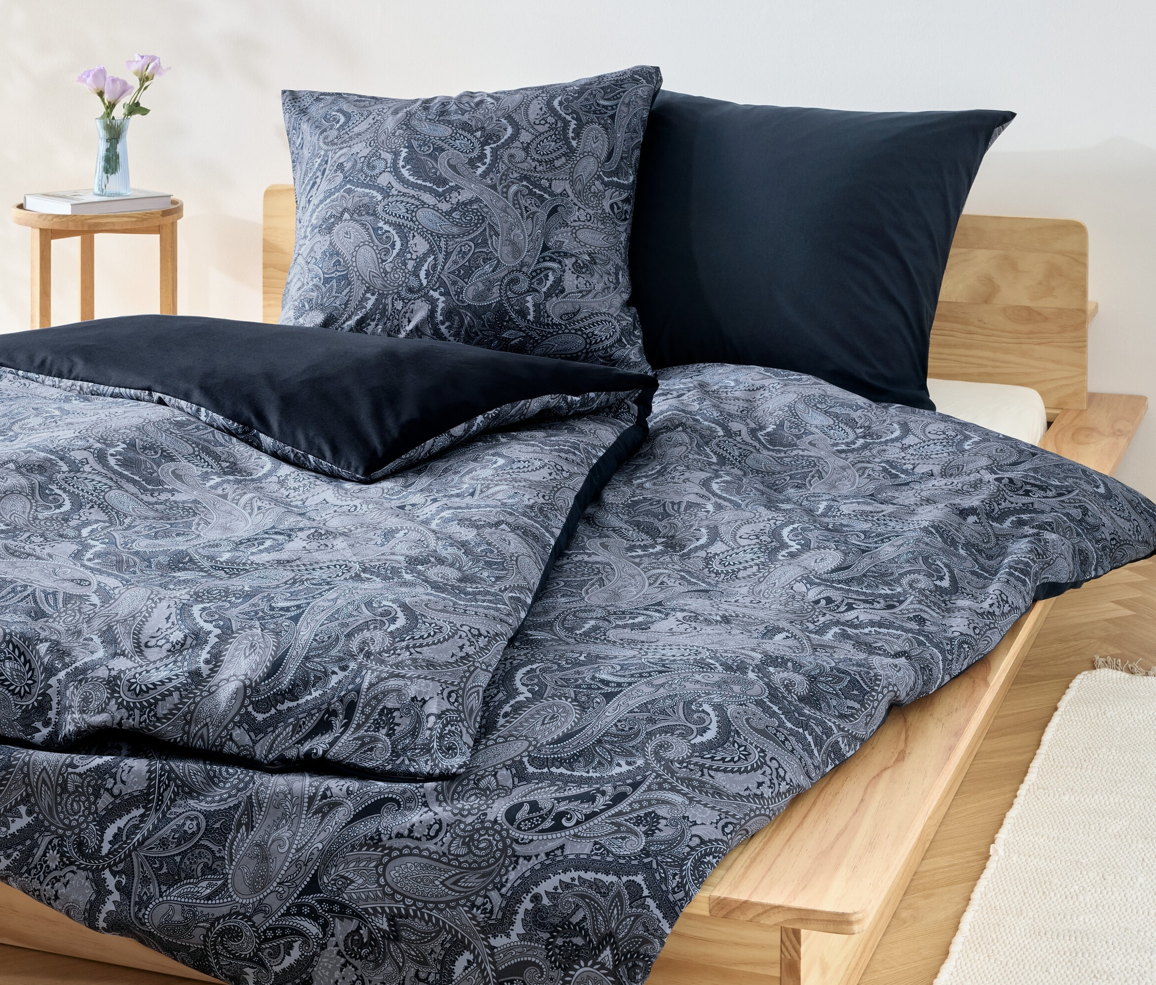 Ložní souprava renforcé modré barvy s květinovým vzorem a jednobarevnými modrými polštáři na dřevěné posteli.