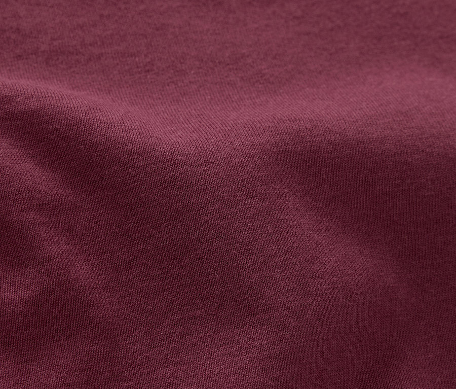 Detailní záběr na vínově červenou látku s texturou.