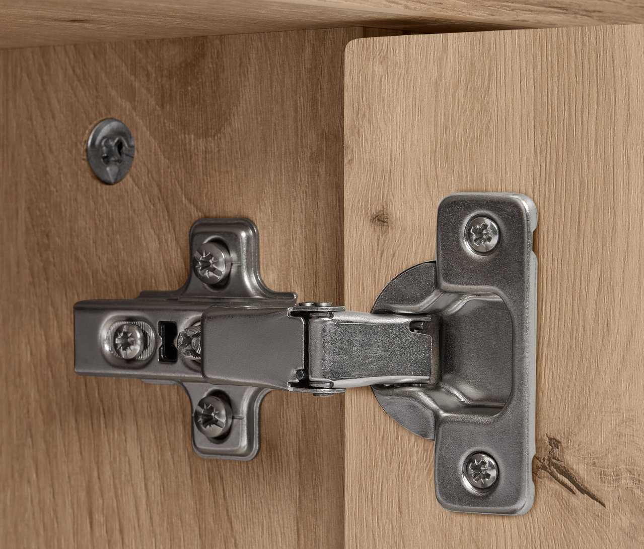 Detail stříbrného pantu na dřevěném REET sideboardu.