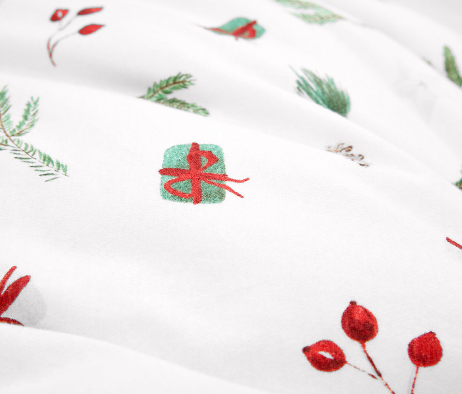 Detail látky s vánočním motivem, zelené větvičky a červené bobule.