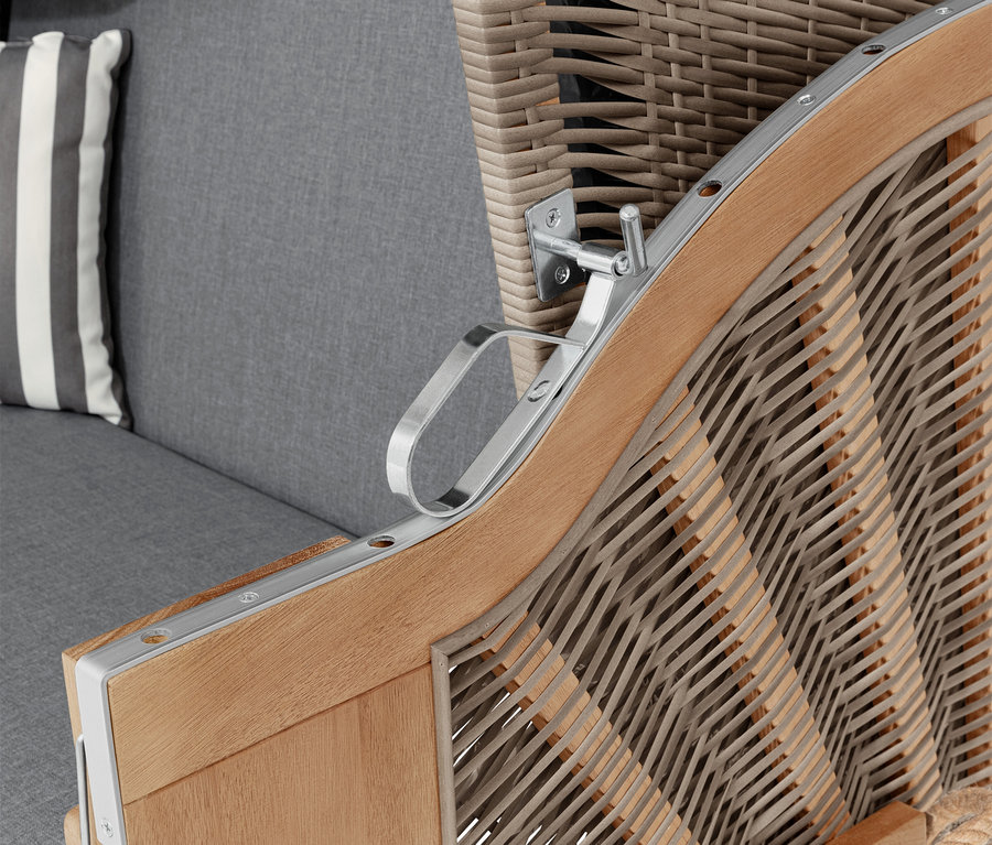 Detail plážového koše s područkou, šedým polštářem a pruhovaným polštářem.