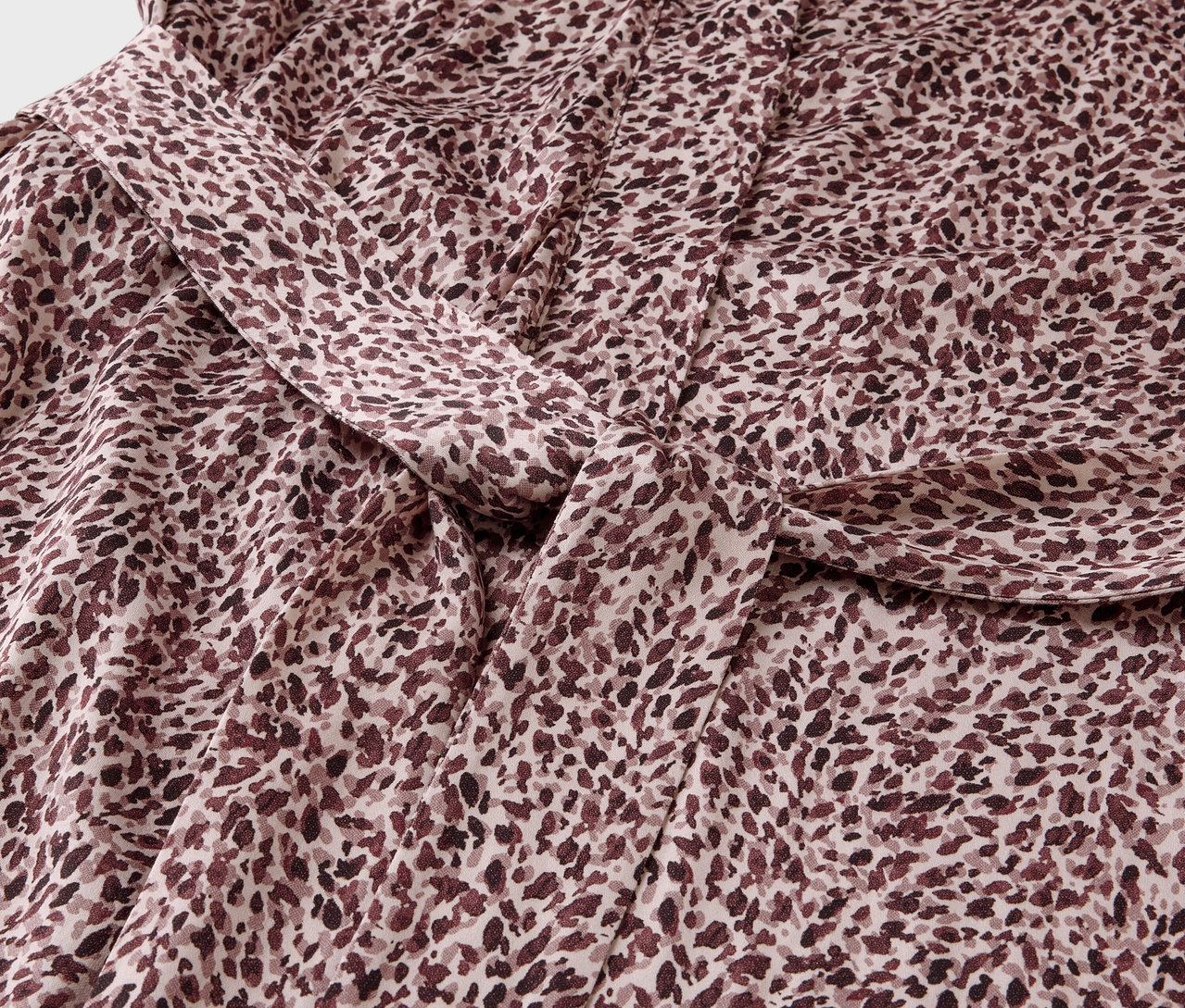 Detailní záběr na látku s hnědým skvrnitým vzorem a uzlem.
