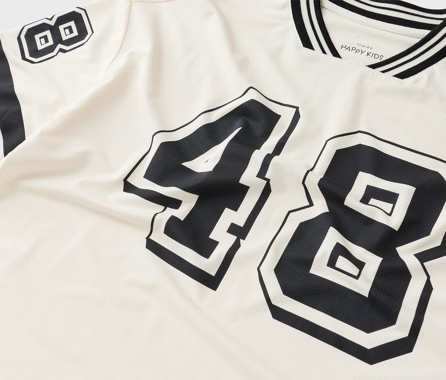 Detail trička s číslem 48 v černé barvě na krémové látce.