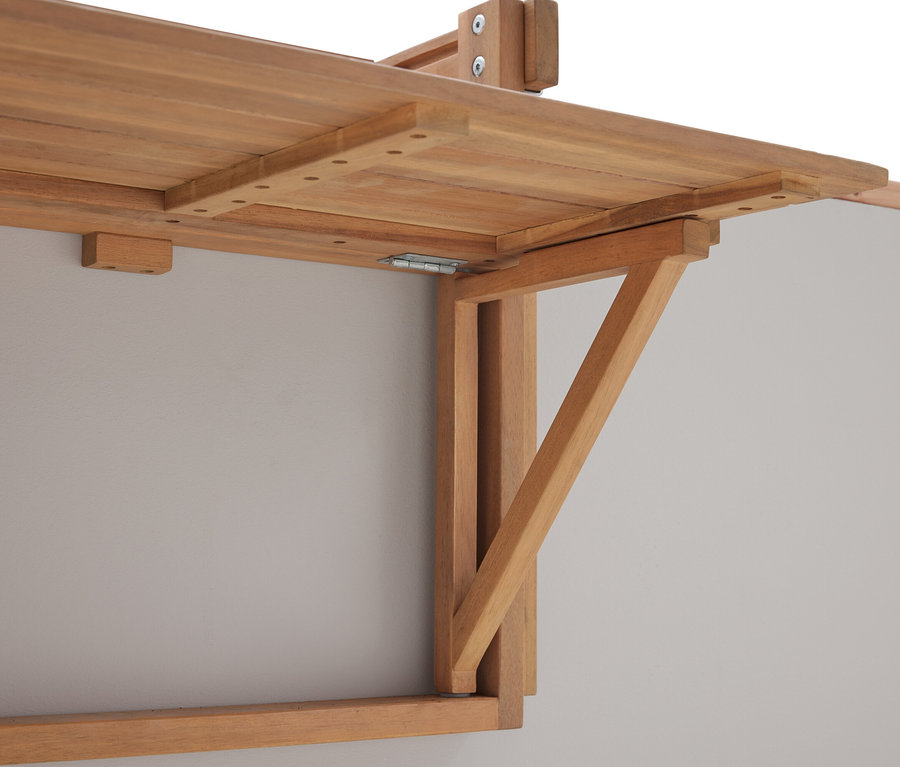 Detail skládacího dřevěného stolu namontovaného na šedé stěně.