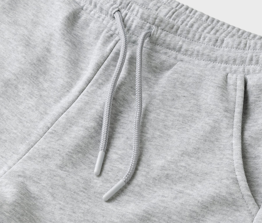 Detailní záběr šedých tepláků se stahovací šňůrkou a kapsou.