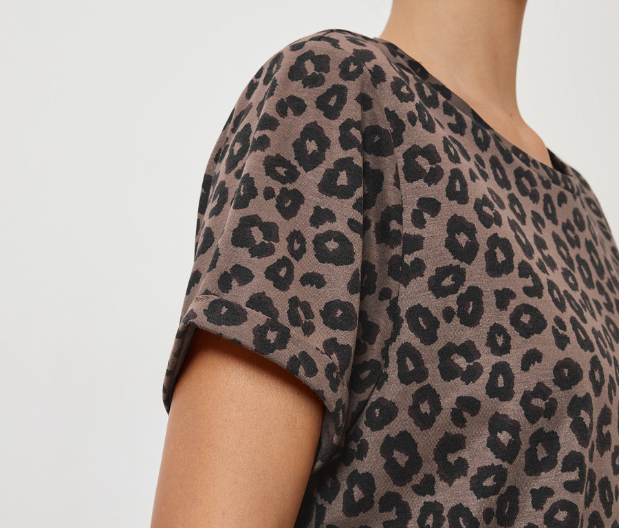 Detailní záběr osoby v hnědém tričku s černým leopardím vzorem.
