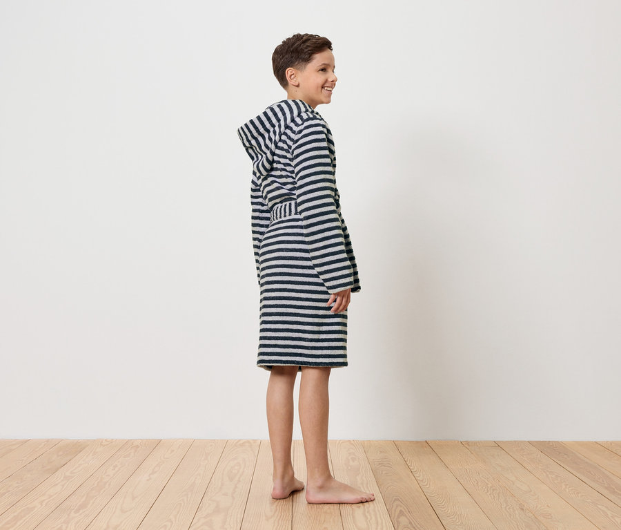 Chlapec stojí bosý v pruhovaném županu.