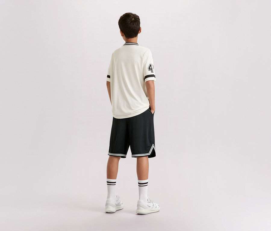 Mladík stojí zády ke kameře, má na sobě světlé tričko s číslem 4, černé šortky, bílé ponožky a tenisky.