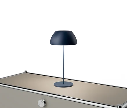 Modrá lampa stojí na béžovém stole se stříbrnými akcenty.