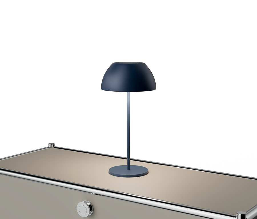 Modrá lampa stojí na béžovém stole se stříbrnými akcenty.