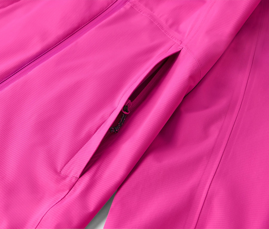 Detailní záběr růžové bundy s kapsou na zip.