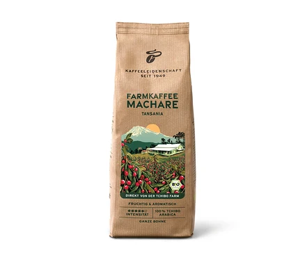 Hnědý papírový sáček Farmářská káva Machare − 500 g zrnkové kávy, s ilustrací kávové farmy s červenými třešněmi, bílým domem a horou. Text: „Tansania“, „Fruchtig & Aromatisch“, „100% Tchibo Arabica“.