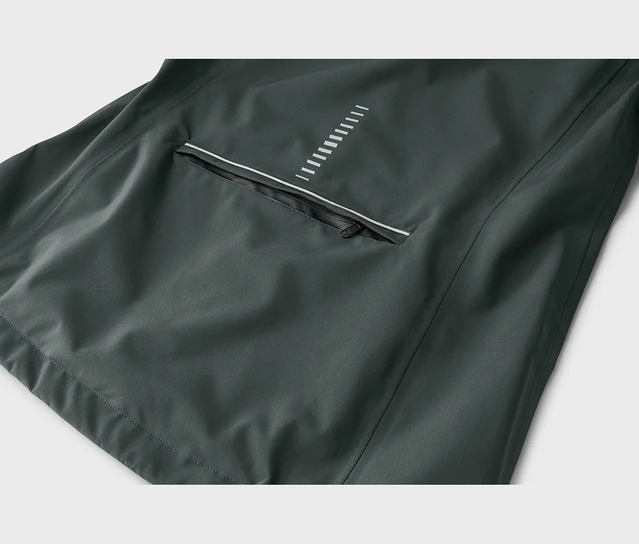 Detail tmavě šedé bundy s kapsou na zip, bílým reflexním proužkem a vzorem bílých svislých čar nad ní.