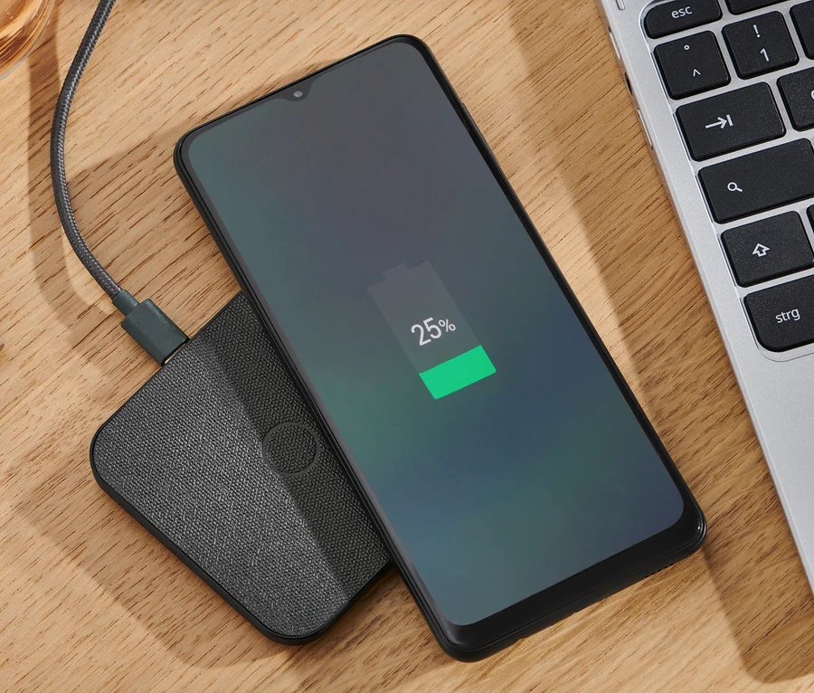 Mobilní telefon se nabíjí na antracitové bezdrátové nabíjecí stanici.