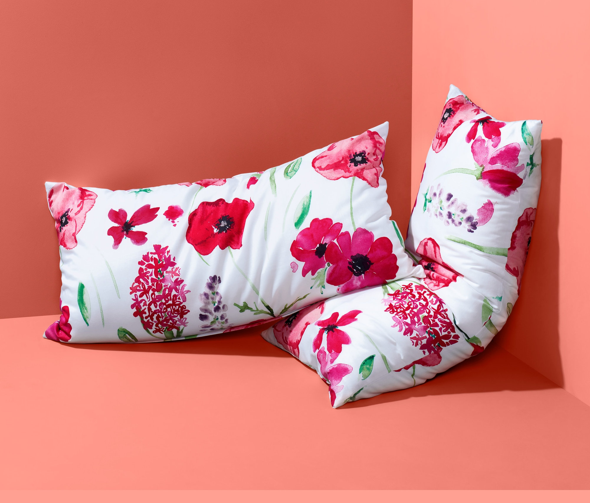 Dva květinové povlaky na polštáře renforcé leží v rohu.