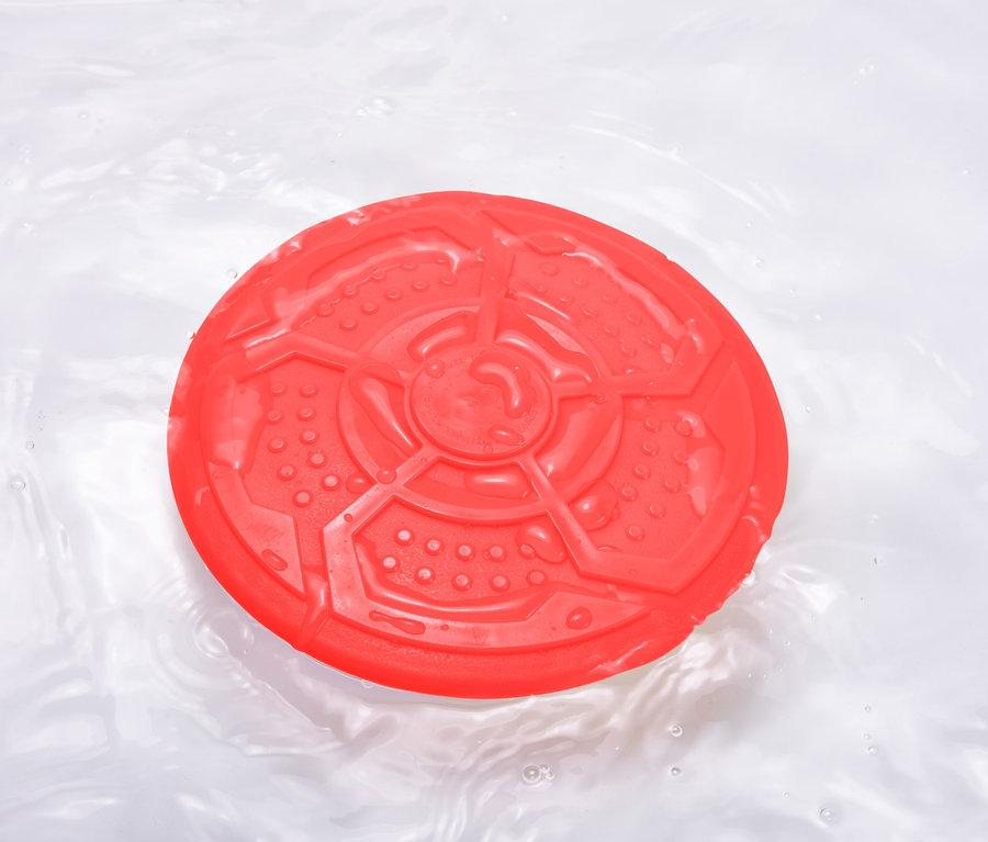 Červený létající talíř pro psy plave na vodě.