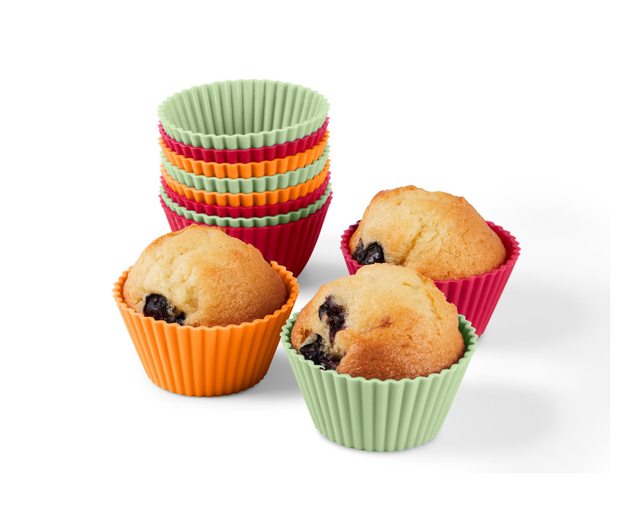 Hromada 12 formiček na muffiny a tři muffiny v oranžové, růžové a zelené formičce.