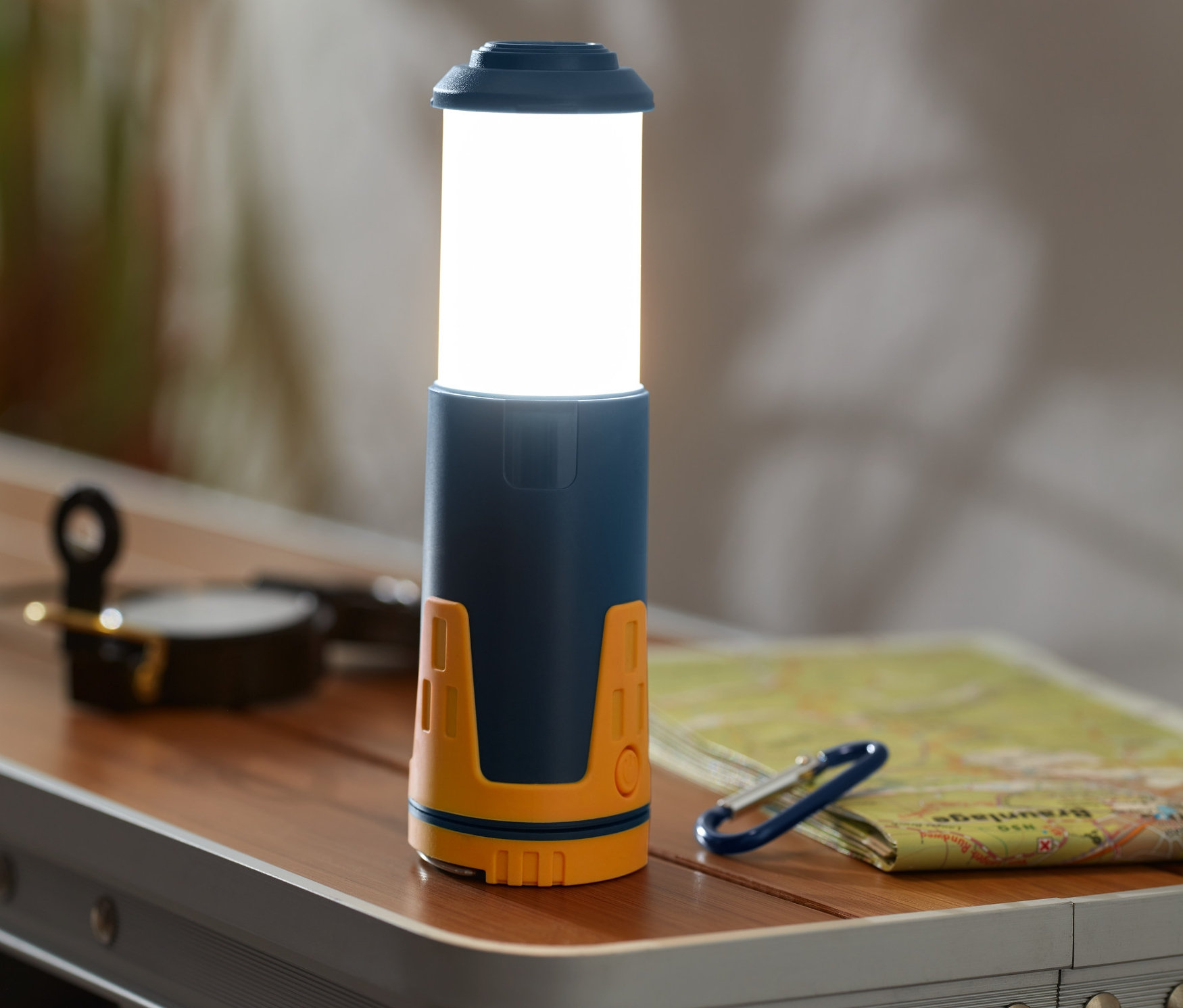 Na stole leží teleskopické kempingové svítidlo.