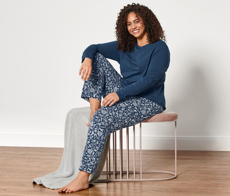 Žena sedí na stoličce v modrém pyžamu.