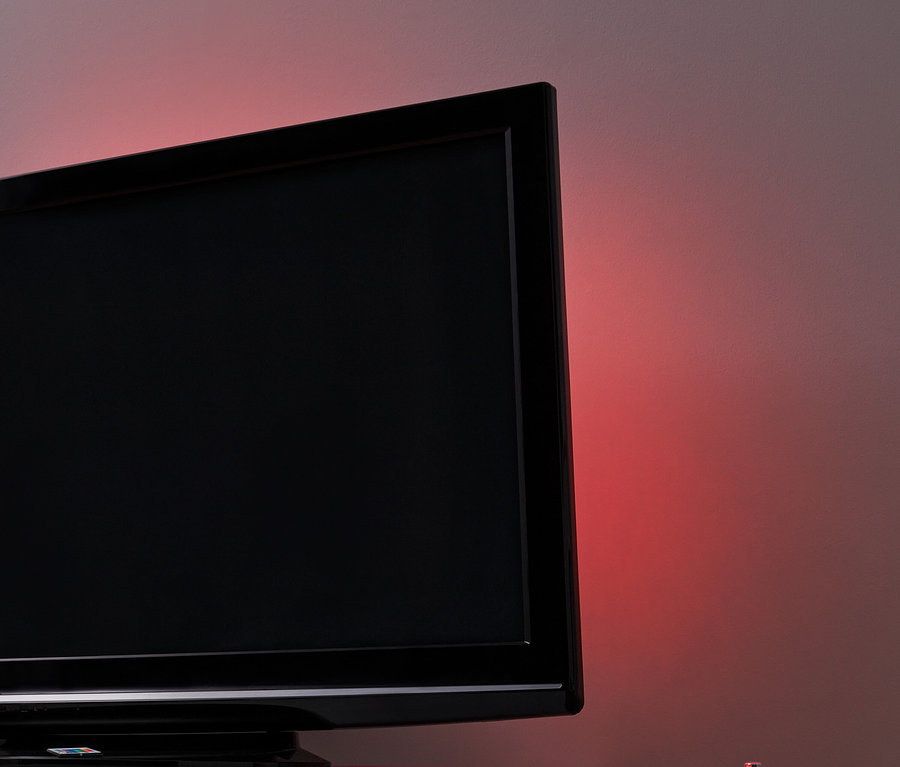 Černá televize s LED podsvícením pro TV na bílém stolku.
