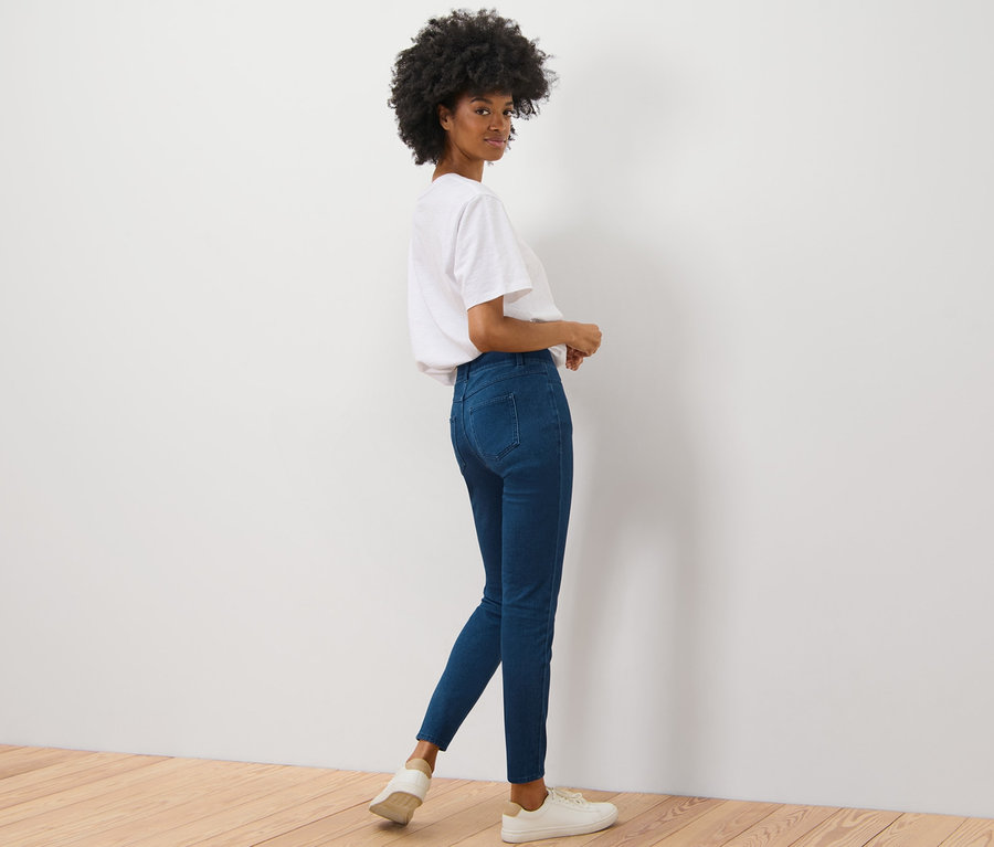 Žena se dívá přes rameno a pózuje v džegínách.