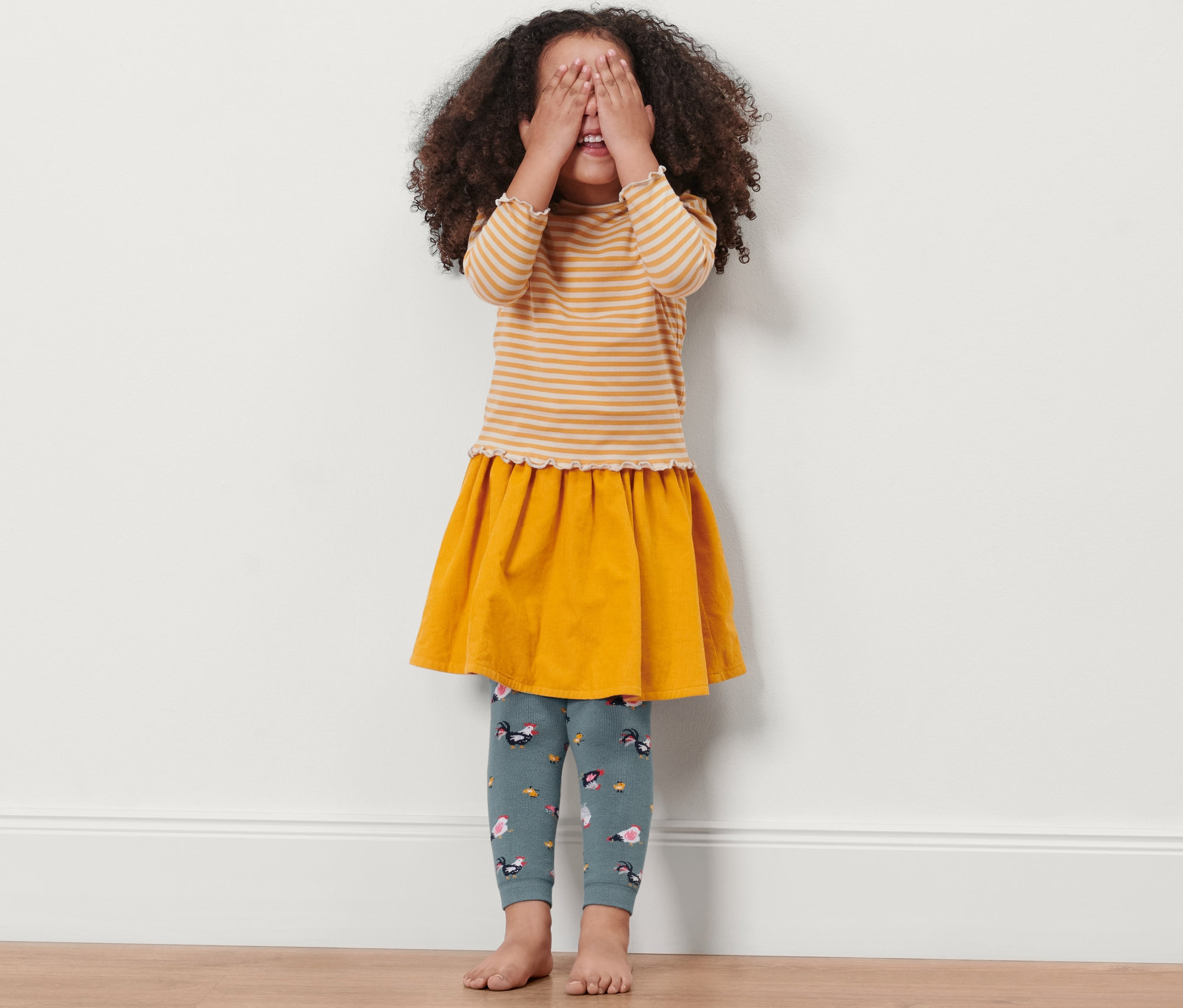 Dívka si zakrývá oči a má na sobě termolegíny se slepičkami.