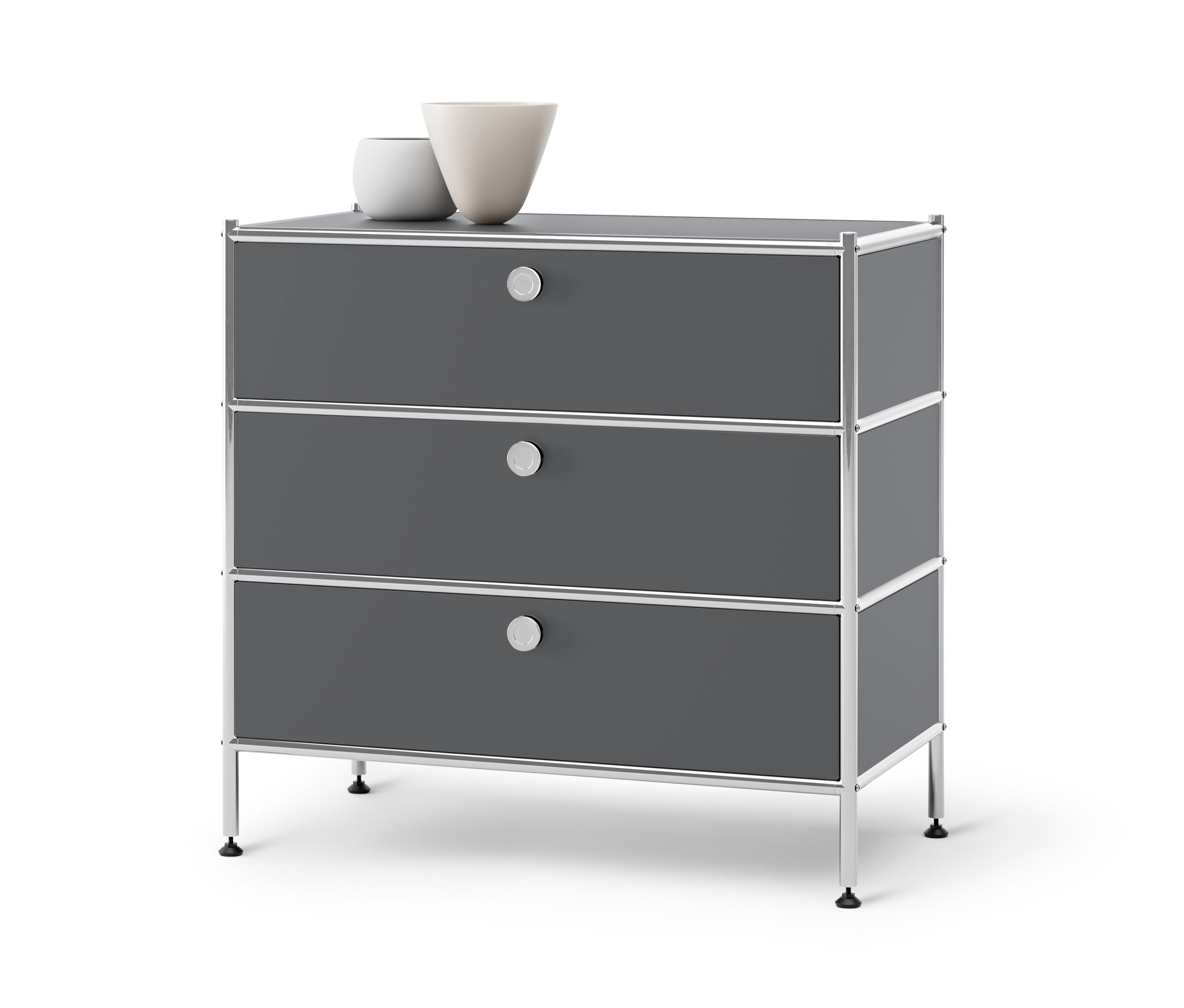 Šedá kovová komoda »CN3« se 3 zásuvkami. Nahoře stojí dvě vázy.