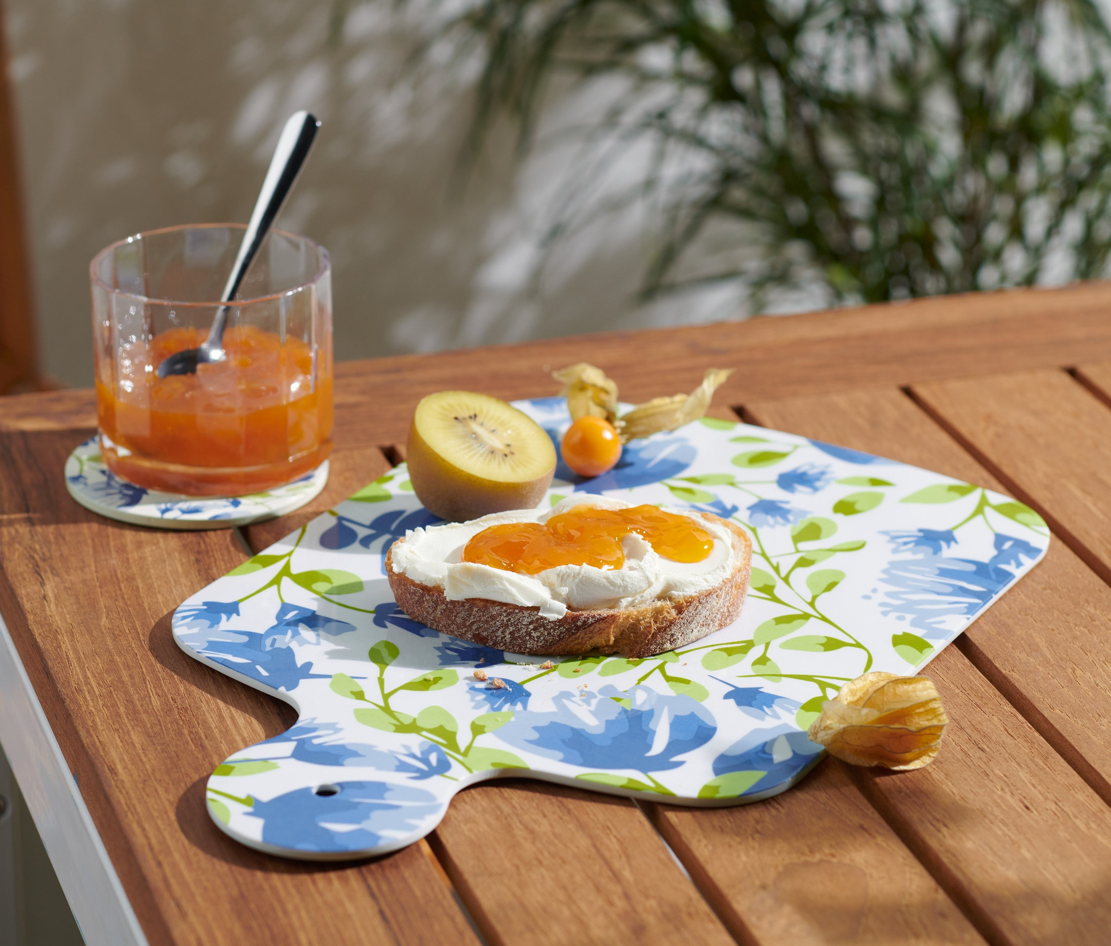 Sklenice džemu a chleba s džemem na servírovacím prkénku.