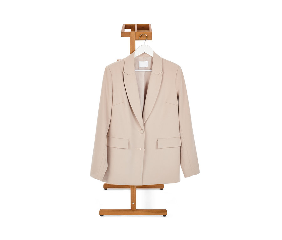 Béžové sako visí na němém sluhovi.