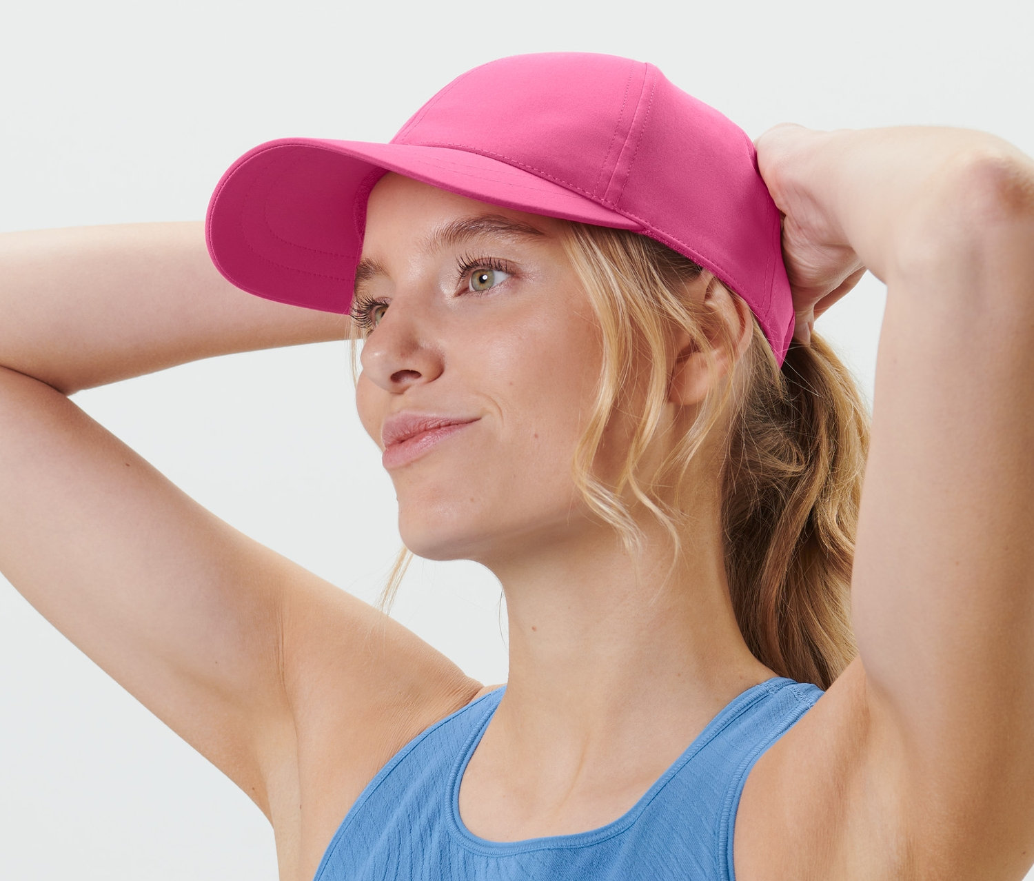 Blondýna si upravuje růžovou sportovní kšiltovku.