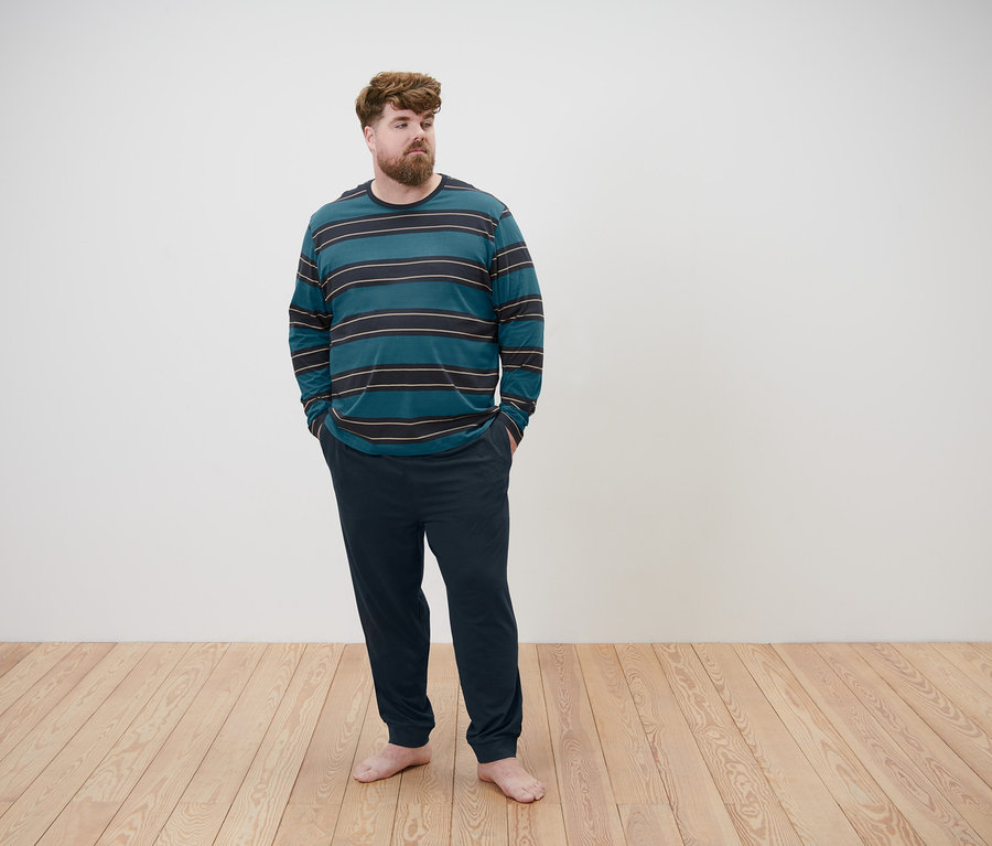 Muž stojí a má ruce v kapsách. Oblečený má pyžamo.