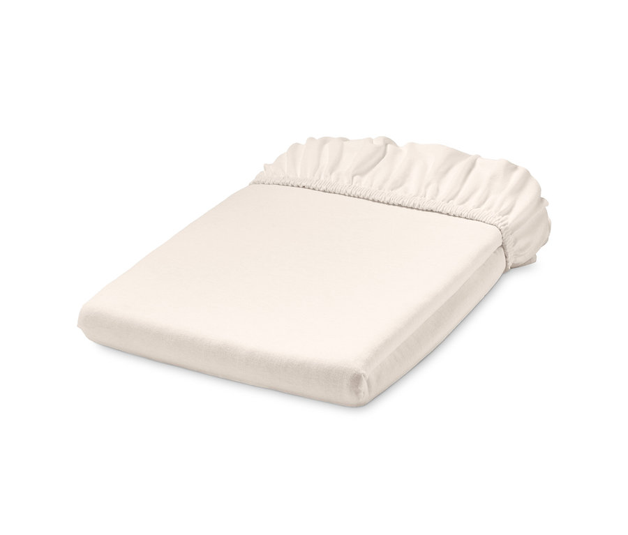 Složené bílé jerseyové napínací prostěradlo standardní velikosti.