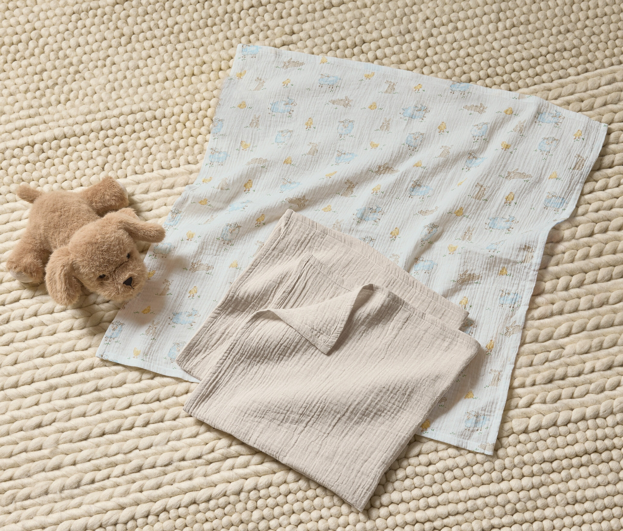 Plyšový pejsek a dětské mušelínové šátky (3 ks) na pleteném koberci.