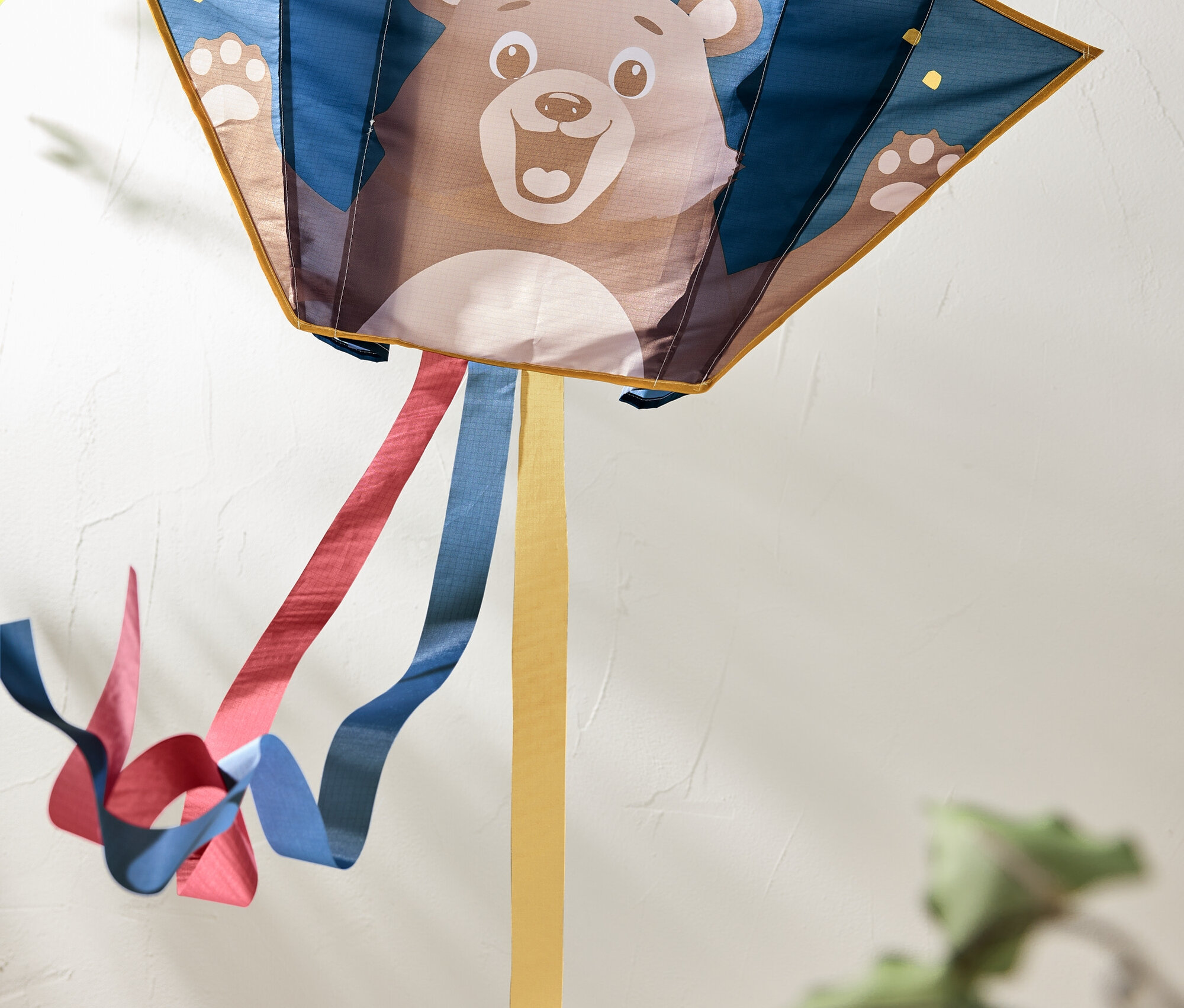 Drak s obrázkem medvěda a barevnými stuhami vlajícími za ním.