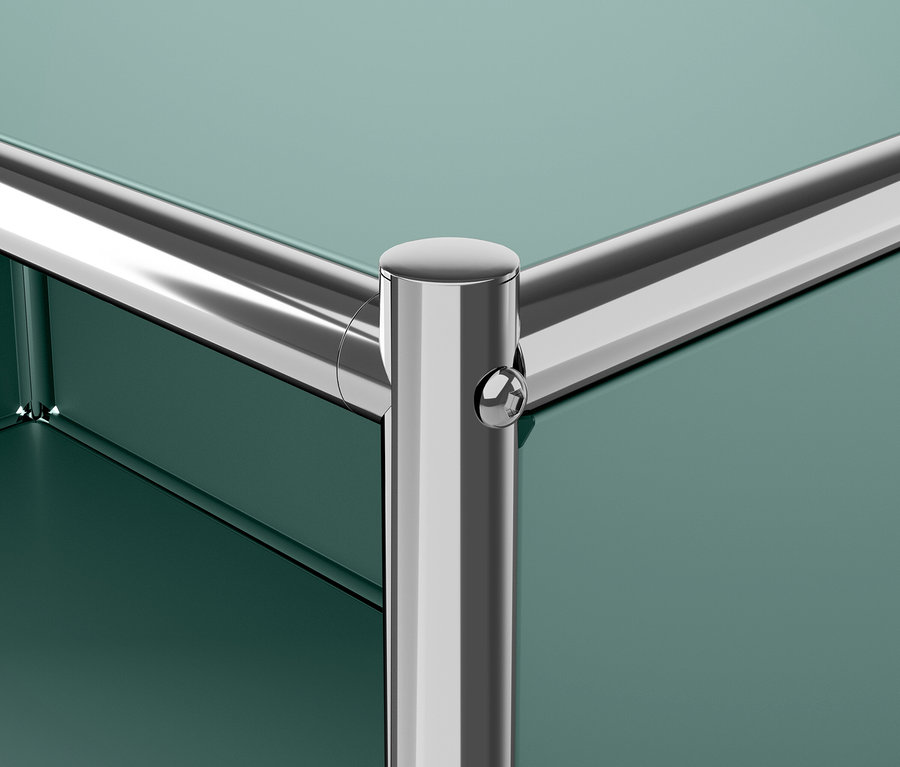 Detail rohu zeleného nábytku s chromovanou nohou.
