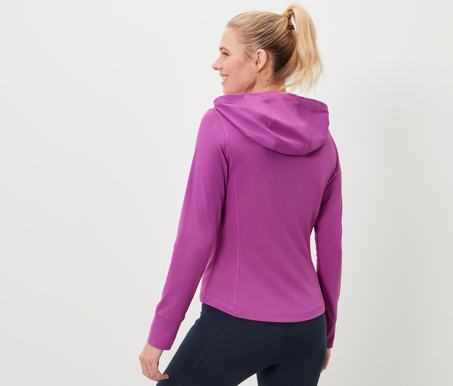 Žena má na sobě sportovní bundu a tmavě modré legíny.