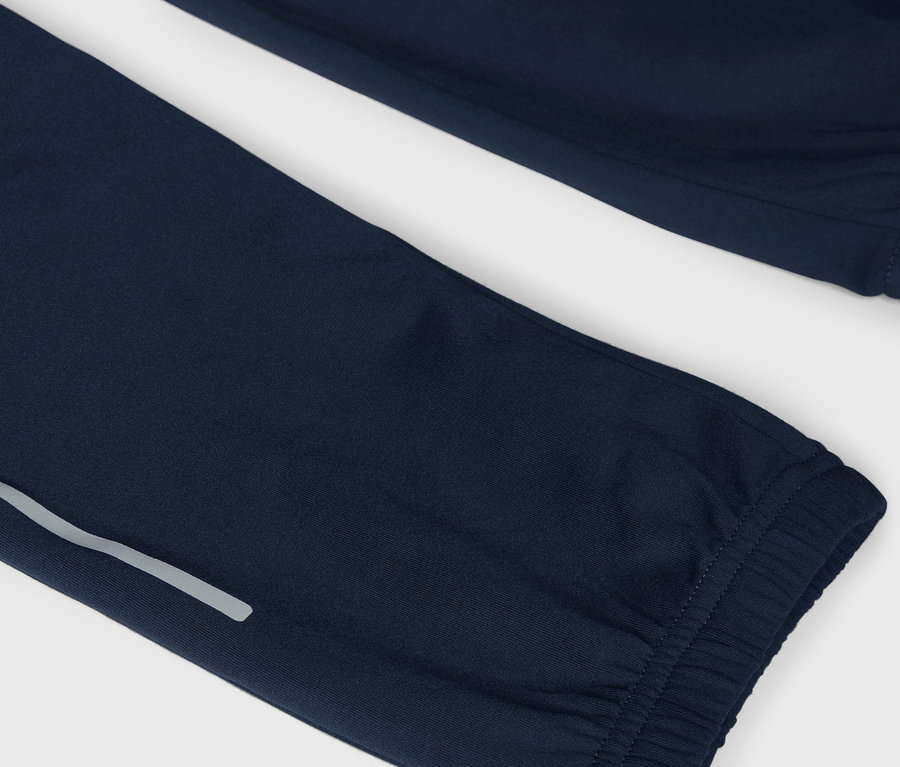 Detail tmavě modrých tepláků s reflexním pruhem.