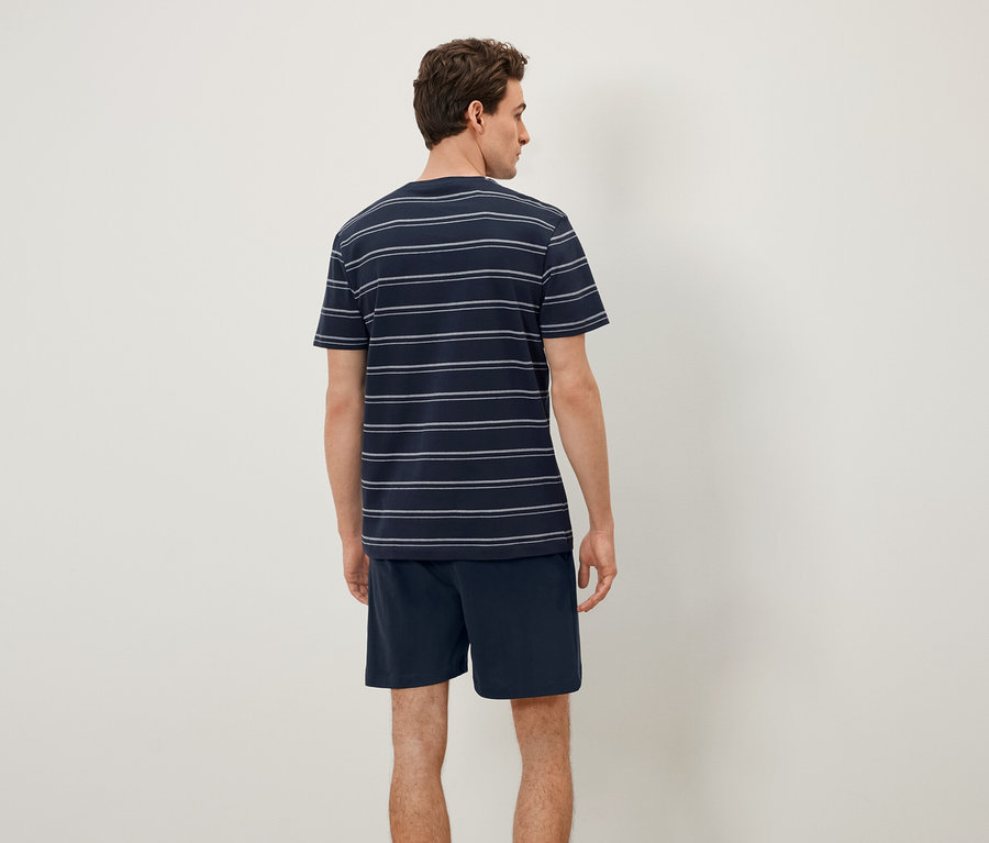 Muž zády k fotoaparátu má na sobě pruhované tričko a šortky.