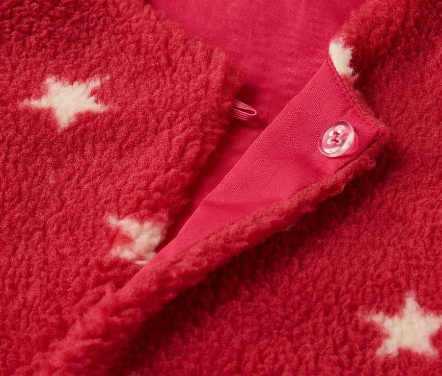Detail červené dětské teddy vesty s bílými hvězdami a zapínáním na knoflík.