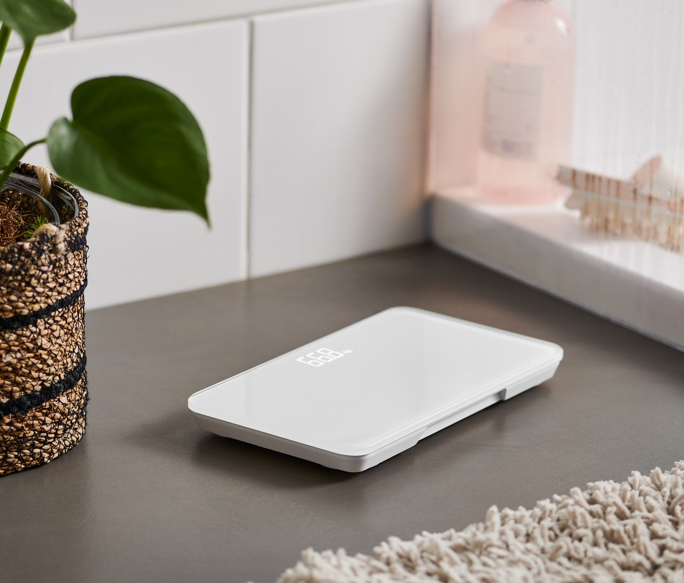 Na šedé podlaze leží ultrakompaktní osobní váha.