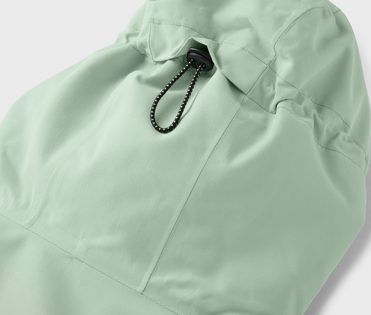 Detail kapuce světle zelené bundy se stahovací šňůrkou.