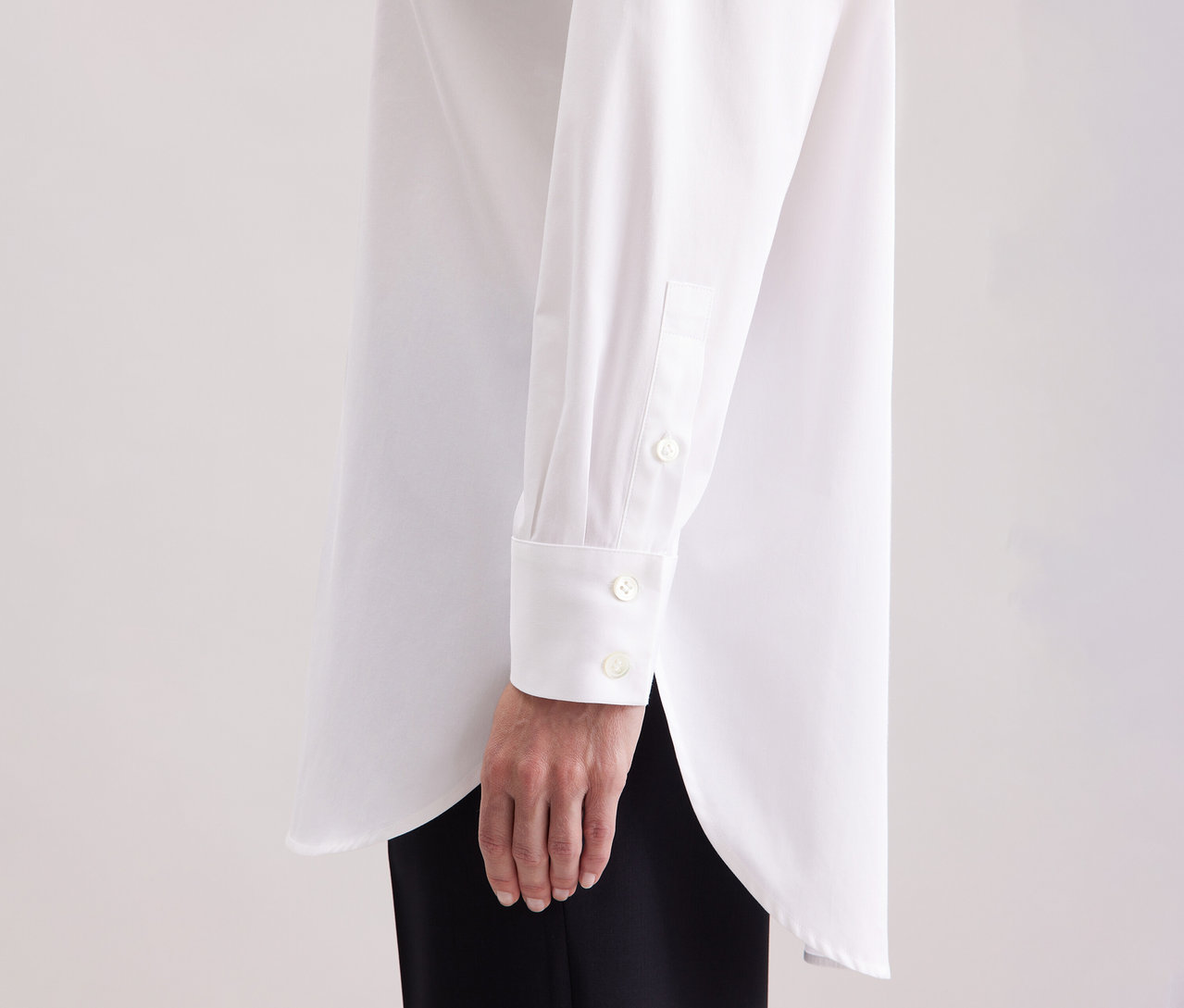 Žena má na sobě bílou dlouhou halenku oversize Seidensticker.