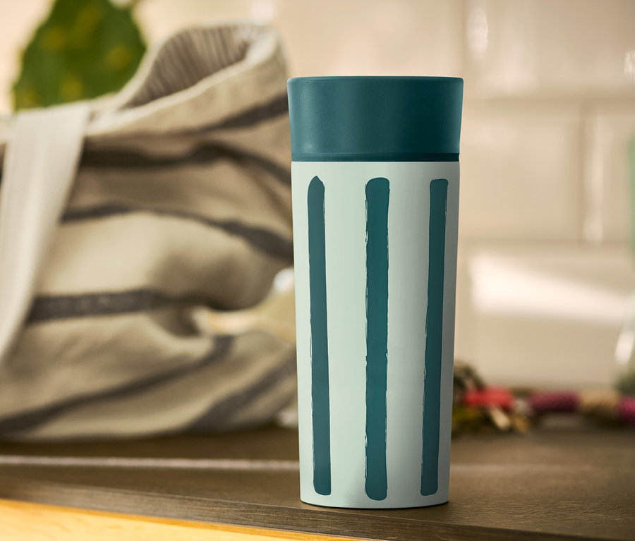 Hrnek Coffee-to-go s pruhy stojí na stole.