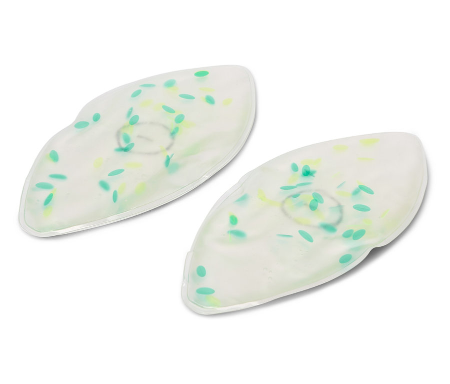 Dvě bílé gelové masky na oči se zelenými a žlutými tečkami leží na bílém pozadí.