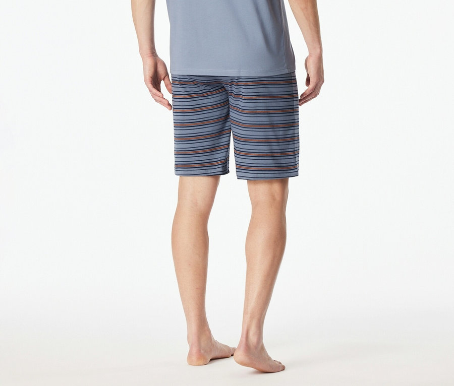 Pohled zezadu na muže v modrém tričku a pruhovaných šortkách na bílém pozadí.